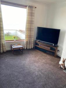 a living room with a flat screen tv and a window at Four waves in Thurso