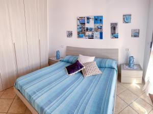 a bedroom with a blue bed with two pillows at Appartamenti La Casina in Porto Azzurro