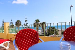 una mesa y sillas con lunares y la playa en HOSTAL LA ESTACION, en Benajarafe
