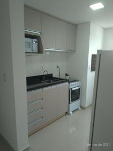 a white kitchen with a sink and a stove at AP 2 dormitórios NOVO em Montenegro edif Malta 302 in Montenegro