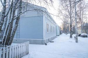 een blauw gebouw met sneeuw op de grond naast een hek bij Cozy 1 Br Apt and Free parking by the Railway station in Oulu