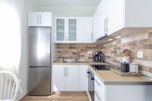 a kitchen with white cabinets and a stainless steel refrigerator at Hestia Harmony Living in Limenaria