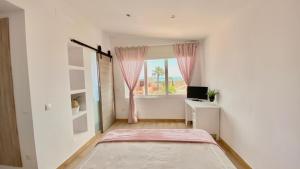 Dieses weiße Zimmer verfügt über ein Fenster, ein Bett und einen Schreibtisch. in der Unterkunft Villa Ana María in Torremolinos