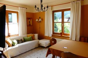 ein Wohnzimmer mit einem weißen Sofa und 2 Fenstern in der Unterkunft Ferienwohnungen Familie Wetzlinger in Bad Kleinkirchheim