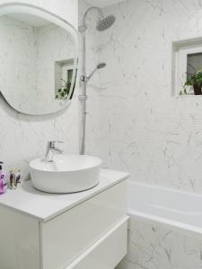 La salle de bains blanche est pourvue d'un lavabo et d'un miroir. dans l'établissement Zen Life Luxury Apartment - Herastrau, à Bucarest
