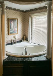 a large white tub in a bathroom with a window at Woodstock Inn Bed & Breakfast in Independence +32 photos