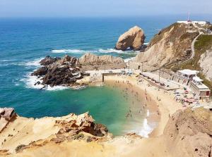 a group of people on a beach near the ocean at Silver Coast Beach House in Torres Vedras
