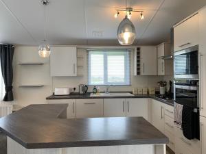 eine Küche mit weißen Schränken und einer Arbeitsplatte in der Unterkunft 2 Bedroom Luxury Lodge, OG30, Shanklin, Isle of Wight in Shanklin