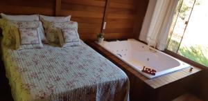 a bed with a bath tub next to a window at Recanto Della Mata in Venda Nova do Imigrante