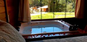 a bath tub in a bedroom with a window at Recanto Della Mata in Venda Nova do Imigrante