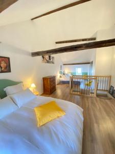 a bedroom with a large white bed with a yellow pillow at Au Pont d’Olt in Saint-Côme-dʼOlt