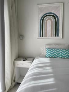 a white bedroom with a bed and a nightstand and a painting at Hotel del Mar in Valeria del Mar