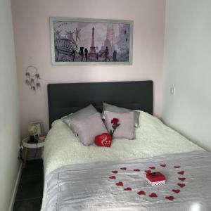 Un dormitorio con una cama con corazones rojos. en La casita de Vanessa en Changé