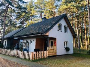 una pequeña casa blanca con techo negro en Domek pod lasem, en Pogorzelica