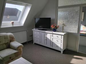 a living room with a television on a white dresser at Ferienwohnung 4 Haus Neptun Ideal für Familien mit Kindern in Büsum