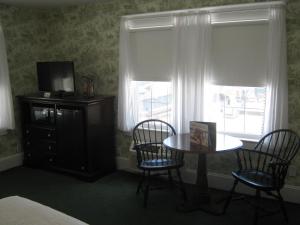 Cette chambre dispose d'une table, de chaises et d'une télévision. dans l'établissement Atlantic Hotel, Inc, à Ocean City