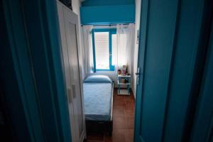 Cette chambre bleue comprend un lit et une fenêtre. dans l'établissement Appartamento a pochi passi dal mare con servizio spiaggia incluso, à Terracine