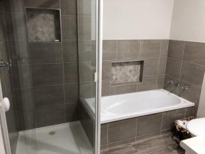a bathroom with a shower with a tub and a sink at Serenity on Sturt in Ballarat