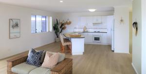 a living room with a couch and a kitchen at Beaches 1 -LJHooker yamba in Yamba