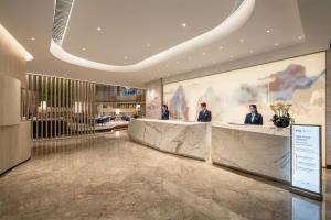 a lobby with two men standing at the reception desk at Holiday Inn - Nanjing South Station, an IHG Hotel in Nanjing