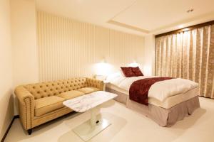 ein Hotelzimmer mit einem Bett und einem Sofa in der Unterkunft Hotel Liberty Matsuyama (Adult Only) in Matsuyama