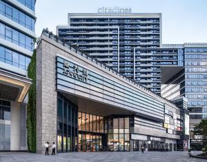 东莞东莞馨乐庭松山湖公寓酒店的一座大型建筑,前面有人