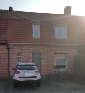 une voiture blanche garée devant un bâtiment en briques dans l'établissement Cozy house, à Turnhout