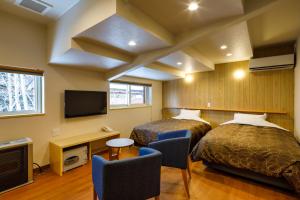 Cette chambre comprend deux lits, un bureau et une télévision. dans l'établissement Aoni Sanso, à Senboku
