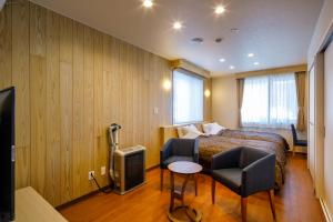um quarto de hotel com uma cama e duas cadeiras e uma televisão em Aoni Sanso em Senboku