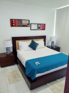 ein Schlafzimmer mit einem Bett mit einer blauen Decke und 2 Lampen in der Unterkunft Cartagena Morros playa edificio frente al mar 1 in Cartagena de Indias