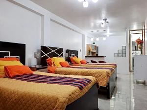Habitación con 3 camas con almohadas de color naranja y amarillo. en Cusco Magico 6 - Mini Departamento Santa Ursula, en Cusco