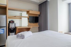DukuhpakisにあるSpacious Studio Room Apartment at Grand Sungkono Lagoon By Travelioのタオルが敷かれたベッドのあるホテルの部屋
