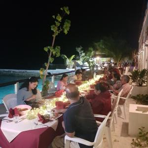 a group of people sitting around a table at night at LVM Bodufolhudhoo in Bodufolhudhoo