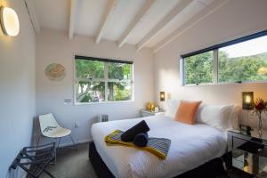 een slaapkamer met een bed, een bureau en 2 ramen bij Number 10 Arrowtown Sleeps 12 in Arrowtown