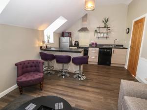 a kitchen with purple chairs and a counter in a room at Tan Bryn 2 in Aberdaron