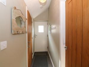 a small hallway with a door and a mirror at Tan Bryn 2 in Aberdaron