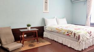 a bedroom with a bed and a chair and a table at 赤嵌厝Child Come Home in Tainan