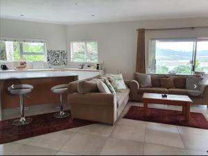 a living room with a couch and a kitchen at Lagoon View Villa in Knysna