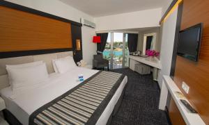 チェシメにあるCesme Ladin Hotelのベッド1台、薄型テレビが備わるホテルルームです。