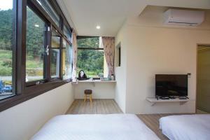 um quarto com uma cama, uma televisão e janelas em New Live B&B em Nanzhuang
