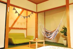 Habitación con hamaca y sofá verde. en Cocomock House en Takayama