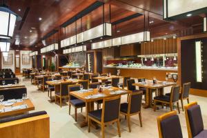 un restaurante con suelo de madera, mesas y sillas en Wanda Jin Suites Changbaishan, en Fusong