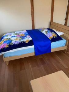 een klein bed met een blauw dekbed erop bij 民泊ドリームルーカー in Haranomachi