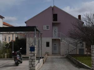 uma casa roxa com uma scooter estacionada à frente dela em Apartment Manigo em Supetar