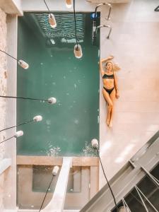 a woman in a bikini sitting on the edge of a swimming pool at Asomaton in Athens