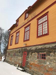 ein orangefarbenes Gebäude mit einer roten Tür im Schnee in der Unterkunft Medstugans vandrarhem in Duved