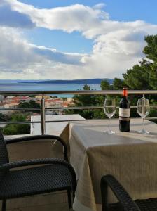 a bottle of wine sitting on a table with two glasses at APARTMAN SUNCE in Baška Voda