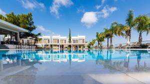 a swimming pool with palm trees and a building at Cosmopolis Multi-Venue in Larnaca
