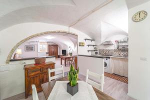 a kitchen and dining room with a clock on a wall at Casa Gilbert 101 in Alghero