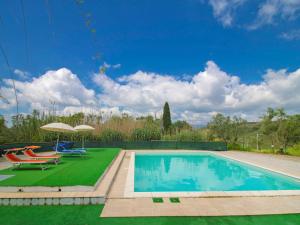 a swimming pool with a table and a chair and an umbrella at Holiday Home Villa Sofia by Interhome in Volterra